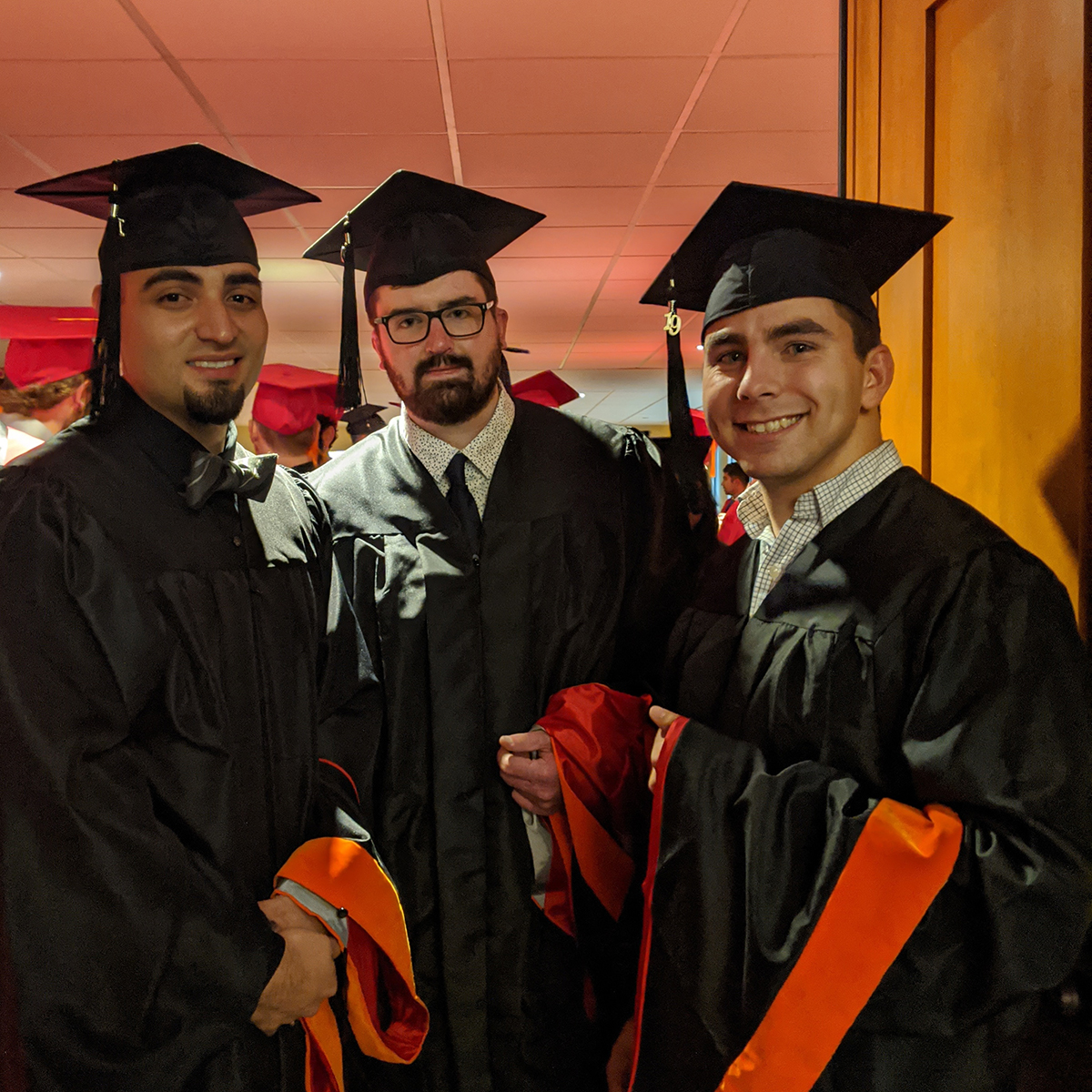 photo of three men at graduation, in graduation attire